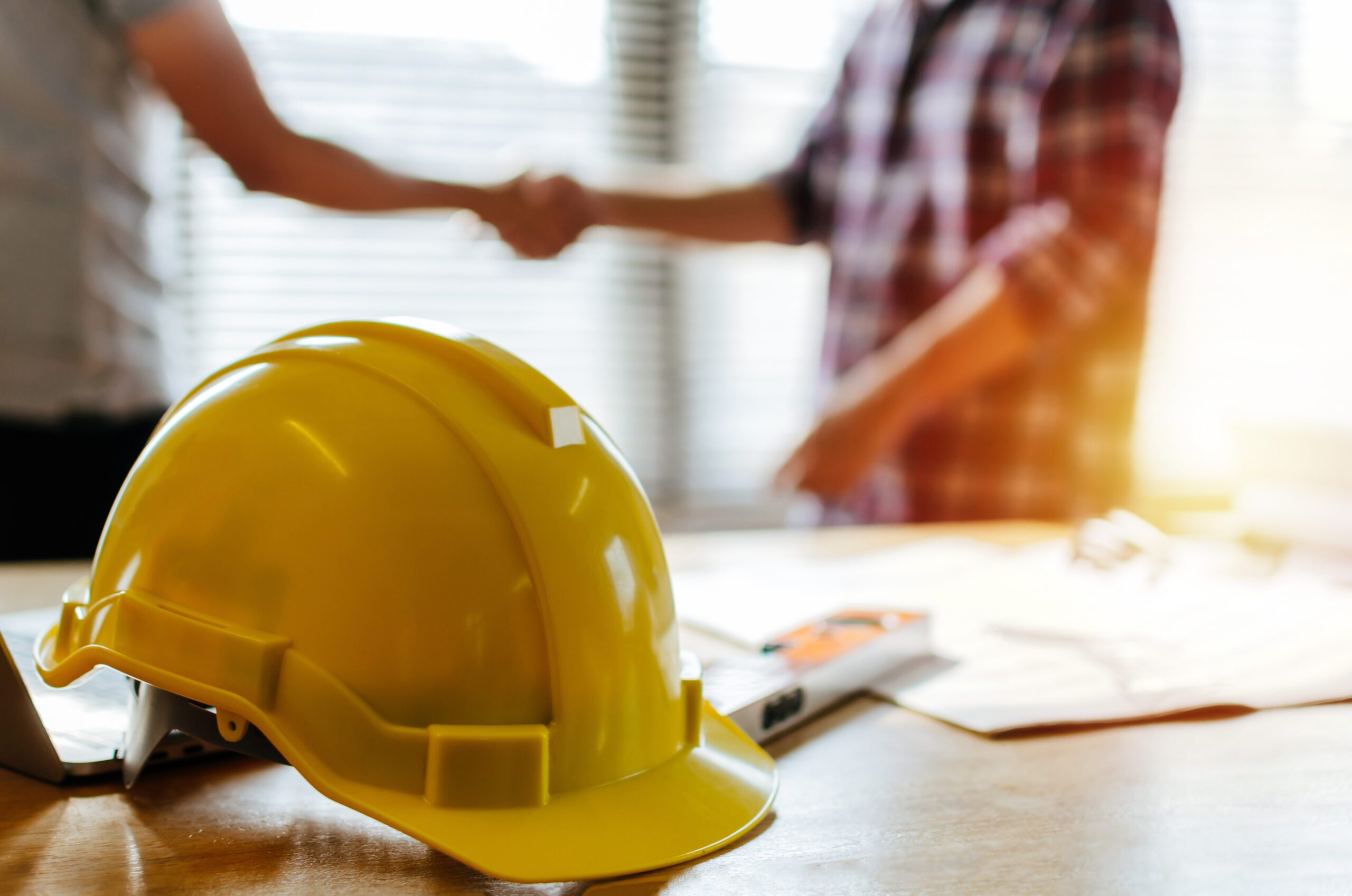 construction worker team hands shaking greeting start up plan new project contract behind yellow safety helmet on workplace desk in office center