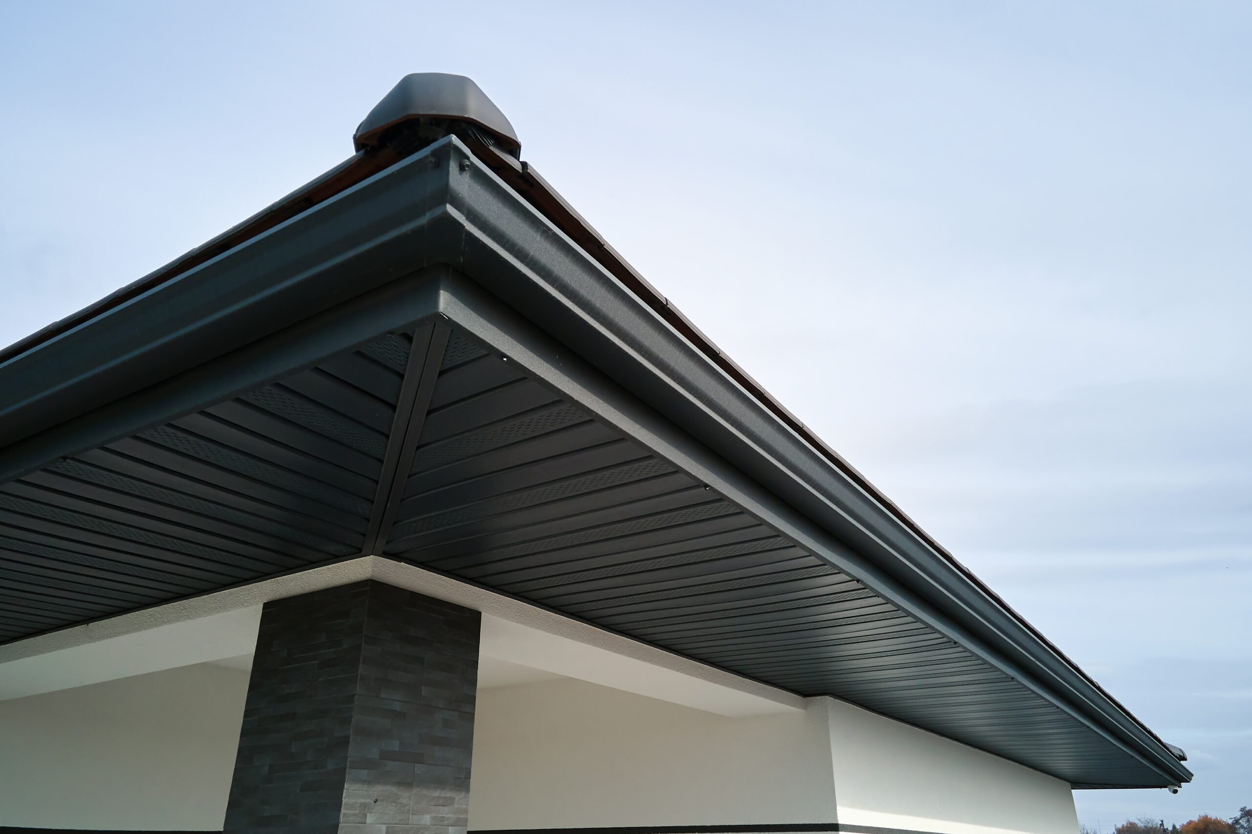 house corner with brown metal planks siding and roof with steel gutter rain system