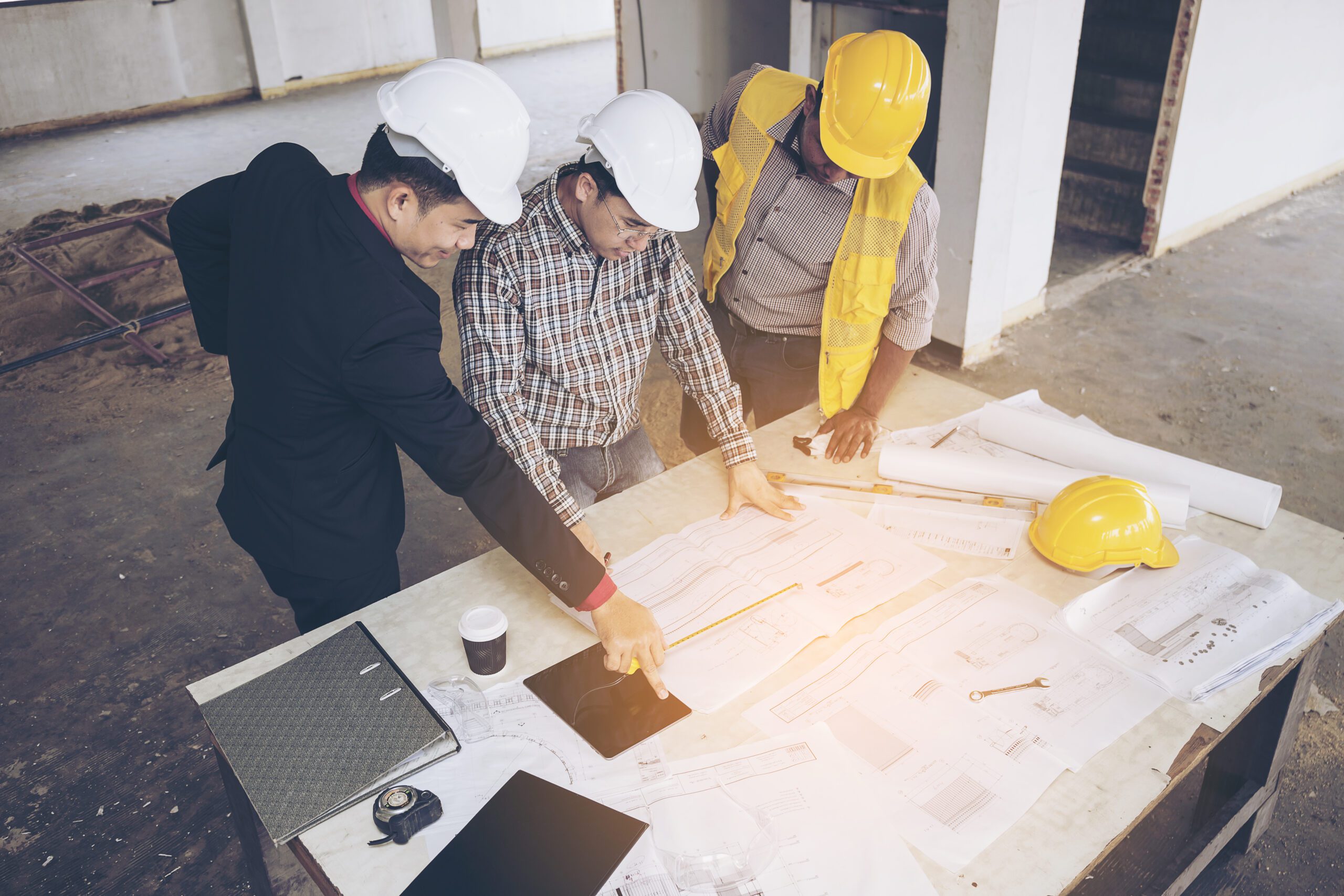 Asian business people group on meeting and presentation in construction site with construction engineer architect and worker looking building model and blueprint plan blueprint plans